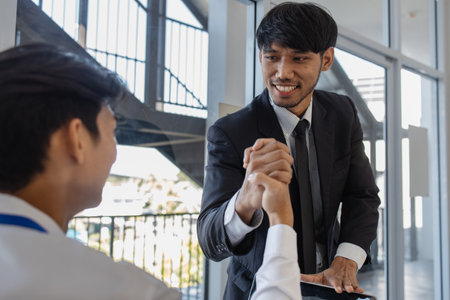 after the businessmen successfully agreed to the merger and signed the contract and they shook hands to express their congratulations, the marketing and accounting departments were shaking handsの写真素材