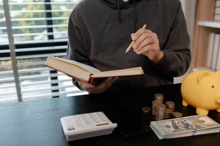 a man is calculating the money from his savings account to buy a house, this man is calculating his finances to plan for buying a house, financial, calculate, income, investmentの写真素材