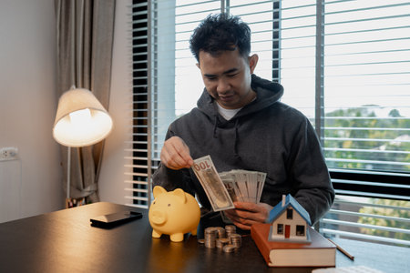 a man uses his savings to buy his dream home, this man plans his finances to buy a home, he uses his savings to buy a home as an investment, financial, money, property, paymentの写真素材