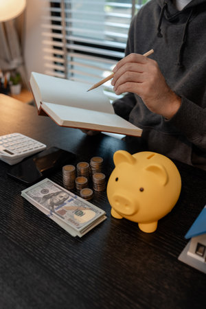 a man is calculating the money from his savings account to buy a house, this man is calculating his finances to plan for buying a house, financial, calculate, income, investmentの写真素材