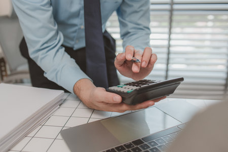 the chief accountant is working hard to check the documents and financial figures to be in accordance with the disbursement report, a businessman is sitting in his private office, calculate, companyの写真素材