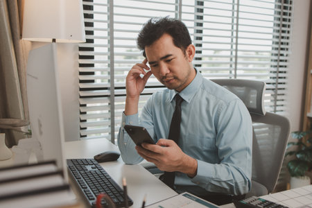 an entrepreneur is feeling stressed while sitting at his office, a businessman is overworked and is accumulating stress, an accounting and finance officer is experiencing extreme stress from workの写真素材