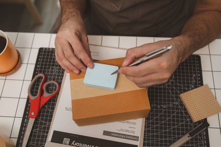 a small online business owner is checking boxes for accuracy before shipping to customers, parcel,...