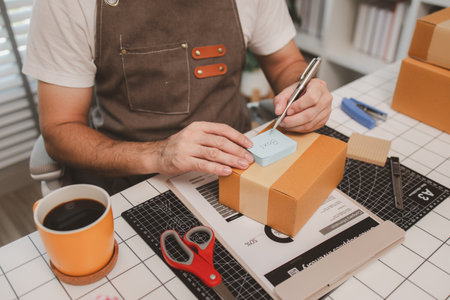a small online business owner is checking boxes for accuracy before shipping to customers, parcel,...