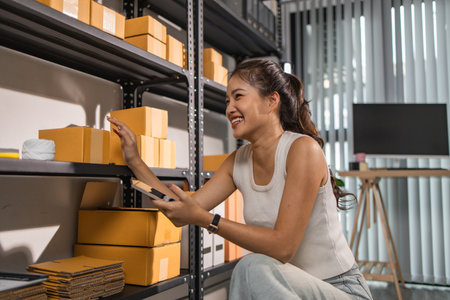 warehouse worker is checking boxes of packaged in the warehouse, a small business owner who runs an online business is packing packages to send to customers, parcel, e-business,の写真素材