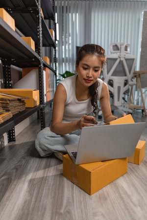 a female employee is checking parcel boxes in a warehouse, a warehouse manager is counting parcel boxes on shelves, a small online business owner is in a storage roomの写真素材