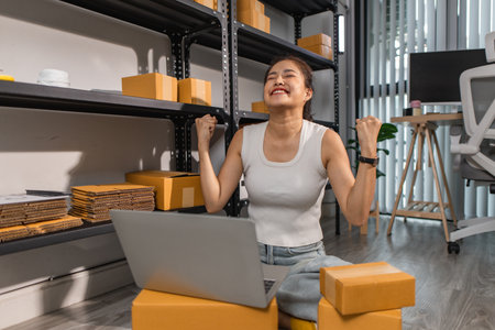 a small online business owner is feeling very happy because her business is successful, the entrepreneur shows her joy while she is in her warehouse, parcel, small business, joyfulの写真素材