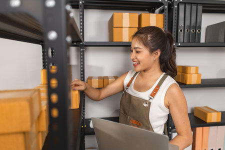 working with parcel boxes in the warehouse, an employee checks the number of parcel boxes in the warehouse, an entrepreneur in shipping business comes in to inspect the storage roomの写真素材