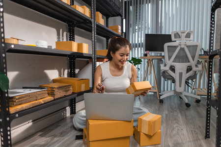 a female employee is checking parcel boxes in a warehouse, a warehouse manager is counting parcel boxes on shelves, a small online business owner is in a storage roomの写真素材
