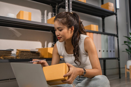 warehouse worker is checking boxes of packaged in the warehouse, a small business owner who runs an online business is packing packages to send to customers, parcel, e-business,の写真素材
