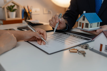 staff is explaining the information about the house lease contract documents to the buyer, the buyer signs the house lease agreement acknowledgment contract with the staff to transfer the ownershipの写真素材