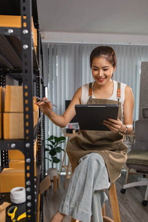 warehouse worker is checking boxes of packaged in the warehouse, a small business owner who runs an online business is packing packages to send to customers, parcel, e-business,の写真素材