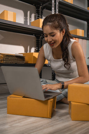 warehouse worker is checking boxes of packaged in the warehouse, a small business owner who runs an online business is packing packages to send to customers, parcel, e-business,の写真素材