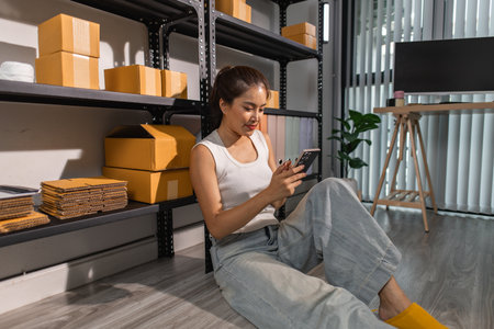 a female employee is checking parcel boxes in a warehouse, a warehouse manager is counting parcel boxes on shelves, a small online business owner is in a storage roomの写真素材
