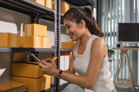 warehouse worker is checking boxes of packaged in the warehouse, a small business owner who runs an online business is packing packages to send to customers, parcel, e-business,の写真素材