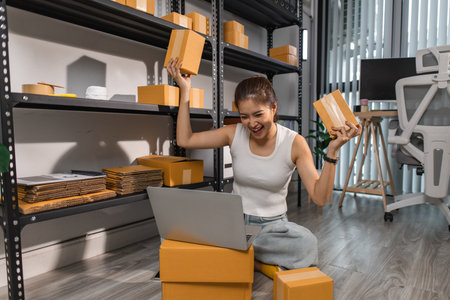 a small online business owner is feeling very happy because her business is successful, the entrepreneur shows her joy while she is in her warehouse, parcel, small business, joyfulの写真素材