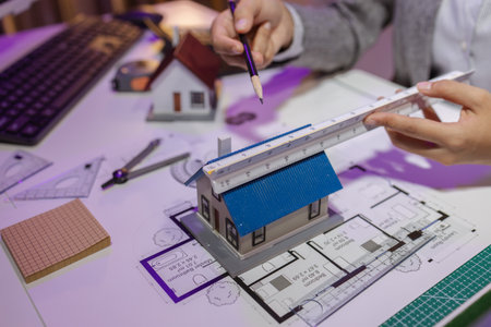 an experienced female engineer is giving a final check to a house model in her private office to...