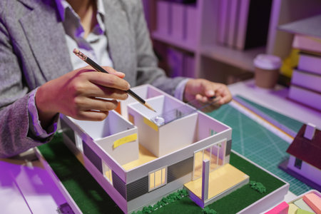 a passionate female architect works in her private office to remodel a house to meet her client's exact needs and meet construction deadlines, house model, engineer, blueprintの写真素材