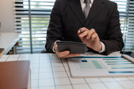 an accountant is calculating financial statements from documents in his private office, finance officer checks company expense documents, businessman works with documentsの写真素材