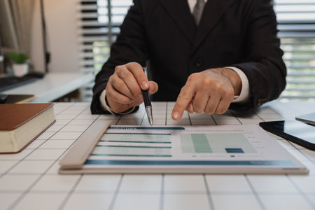 a businessman is studying information in a document to gain a better understanding, a department head is reviewing statistical documents sent by his subordinates, accountant, officeの写真素材