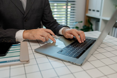 a businessman is sitting at work in his private office, an employee is handling documents to finish on time, accountant, finance, statistics documents, professional, workplaceの写真素材