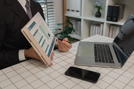 a businessman is studying information in a document to gain a better understanding, a department head is reviewing statistical documents sent by his subordinates, accountant, officeの写真素材
