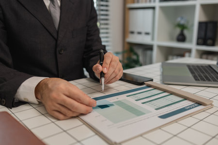 a businessman is sitting at work in his private office, an employee is handling documents to finish on time, accountant, finance, statistics documents, professional, workplaceの写真素材