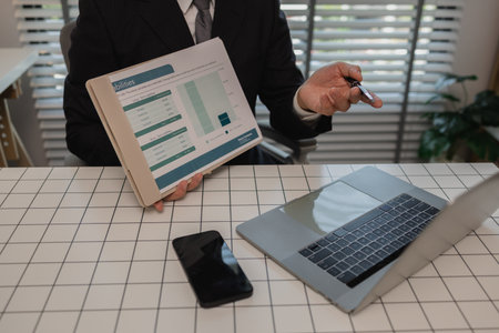 a businessman is studying information in a document to gain a better understanding, a department head is reviewing statistical documents sent by his subordinates, accountant, officeの写真素材