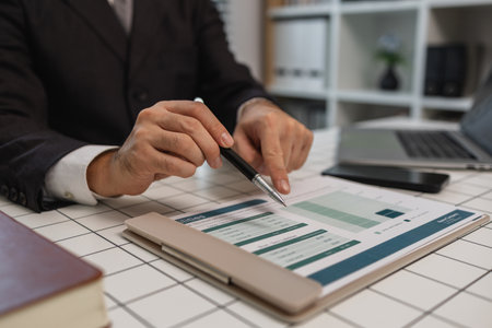 a businessman is studying information in a document to gain a better understanding, a department head is reviewing statistical documents sent by his subordinates, accountant, officeの写真素材