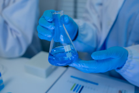 when in a lab, scientists wear lab coats, rubber gloves, and safety goggles, two chemists are testing chemicals in a liquid state, chemists working in a laboratoryの写真素材