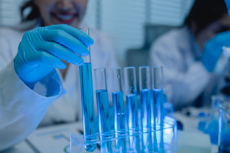 when in a lab, scientists wear lab coats, rubber gloves, and safety goggles, two chemists are testing chemicals in a liquid state, chemists working in a laboratoryの写真素材