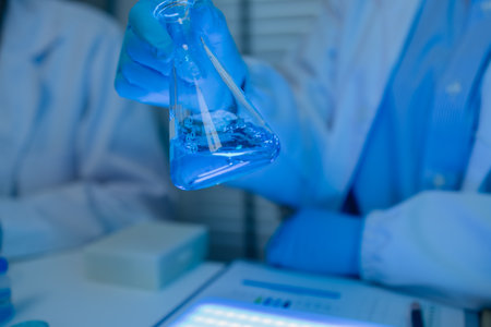 when in a lab, scientists wear lab coats, rubber gloves, and safety goggles, two chemists are testing chemicals in a liquid state, chemists working in a laboratoryの写真素材