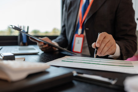 a businessman is reviewing accounting and financial statistics documents in his private office, the statistician prepares various charts and documents for a meetingの写真素材