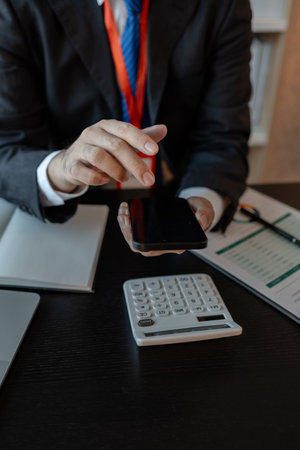 a businessman woks with a foreign company and uses a smartphone to help send and receive information, marketing manager sends statistic information to accounting department via a smartphoneの写真素材