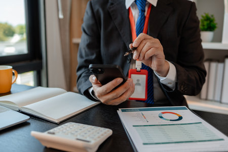a businessman woks with a foreign company and uses a smartphone to help send and receive information, marketing manager sends statistic information to accounting department via a smartphoneの写真素材