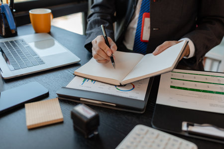 a businessman reviews the company's financial documents in his office, the accountant is rushing to check the figures in the documents before submitting them to the tax officeの写真素材
