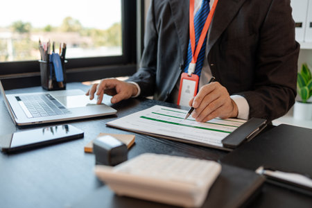 a businessman is reviewing accounting and financial statistics documents in his private office, the statistician prepares various charts and documents for a meetingの写真素材