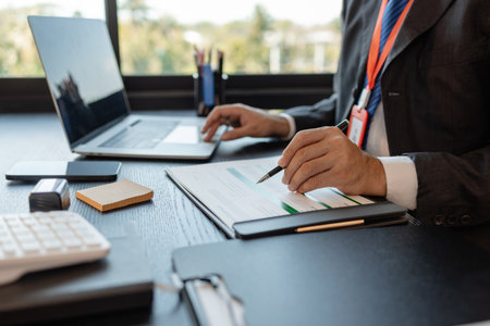a businessman is reviewing accounting and financial statistics documents in his private office, the statistician prepares various charts and documents for a meetingの写真素材