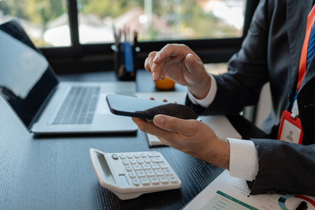 a businessman woks with a foreign company and uses a smartphone to help send and receive information, marketing manager sends statistic information to accounting department via a smartphoneの写真素材