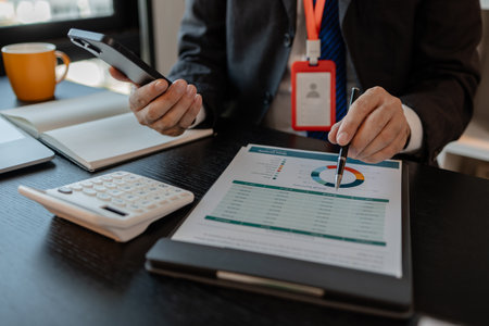 a businessman woks with a foreign company and uses a smartphone to help send and receive information, marketing manager sends statistic information to accounting department via a smartphoneの写真素材
