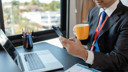 a businessman woks with a foreign company and uses a smartphone to help send and receive information, marketing manager sends statistic information to accounting department via a smartphoneの写真素材