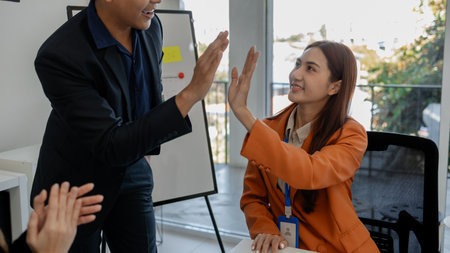 the group of business people showed their joy by clapping and giving high fives because of their...
