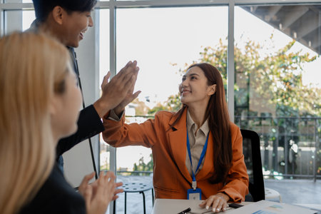 the group of business people showed their joy by clapping and giving high fives because of their success in business, joyful, cheerful, brainstorming in the meeting room, businessmanの写真素材