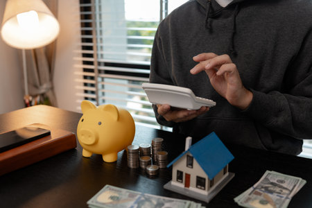 a man is calculating the money from his savings account to buy a house, this man is calculating his finances to plan for buying a house, financial, calculate, income, investmentの写真素材
