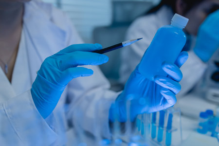 a female chemist is testing various liquid compounds in a lab, a scientist is doing research on the development, she wears a lab coat when she works in laboratory, test tube, scientific equipmentの写真素材