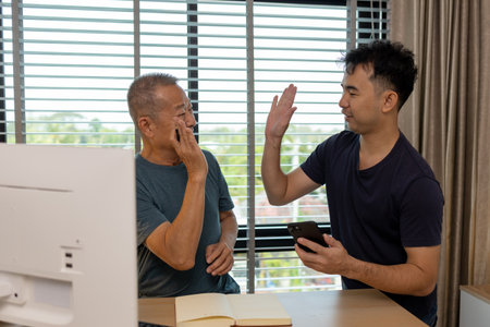 a father and son are spending their free time together at home, the son spends his weekend visiting his elderly father, a family full of love between a father and sonの写真素材