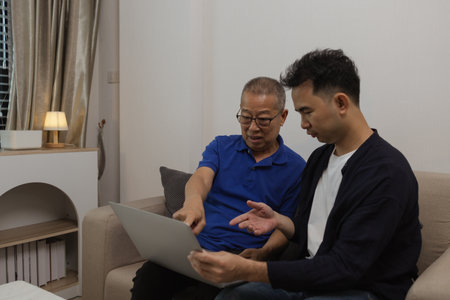 a father and son are spending their free time together at home, the son spends his weekend visiting his elderly father, a family full of love between a father and sonの写真素材