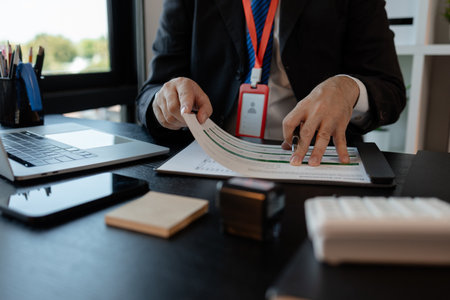 a businessman is reviewing accounting and financial statistics documents in his private office, the...