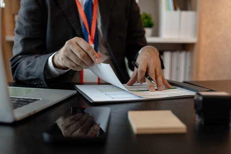 a businessman is reviewing accounting and financial statistics documents in his private office, the...