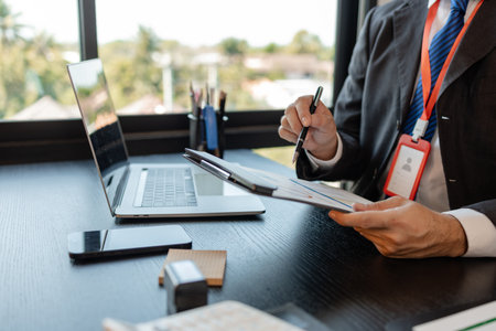 a businessman is reviewing accounting and financial statistics documents in his private office, the...